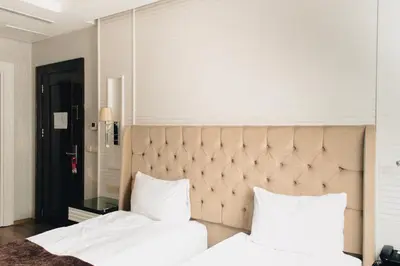 a bedroom with two white beds and a large headboard at City Center Hotel Taksim İstanbul in Istanbul