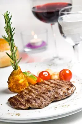 a plate of food with a piece of meat and a glass of wine at Tugcu Hotel Select in Bursa