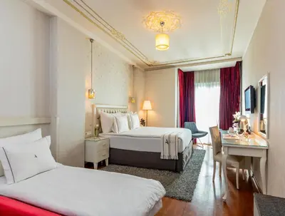 a hotel room with two beds and a desk at Hotel Amira Istanbul in Istanbul