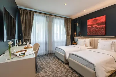 a hotel room with two beds and a desk at Hotel Amira Istanbul in Istanbul