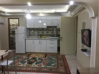 a kitchen with white cabinets and a table and a rug at Bandirma Saglik Apart in Bandırma