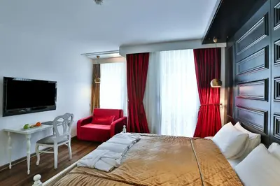 a bedroom with a large bed and a red chair at Senatus Hotel - Special Class in Istanbul