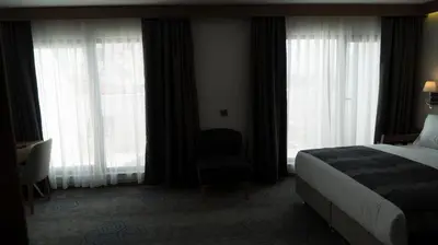 a hotel room with a bed and a chair and windows at Yuksel Istanbul Yenikapı Hotel in Istanbul