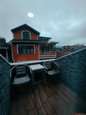 a balcony with two chairs and a table and a house at Hill River Hotel in Agva
