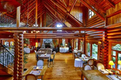a restaurant with tables and chairs in a wooden building at Tranquilla River Lodge in Agva