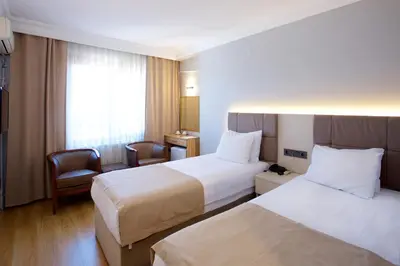a hotel room with two beds and a chair at Grand Ant Hotel in Istanbul