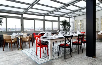 a dining room with red chairs and tables and windows at Darkhill Hotel in Istanbul