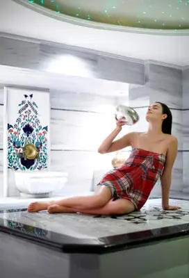 a woman sitting on a counter drinking from a bottle at Darkhill Hotel in Istanbul