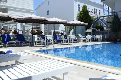 a pool with chairs and umbrellas next to a building at Ascot Hotel Büyükada in Buyukada