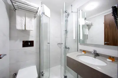 a white bathroom with a sink and a shower at Hotel Eyfel in Istanbul