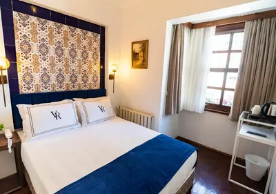 a bedroom with a bed with a blue headboard and a window at Cheers Hostel in Istanbul