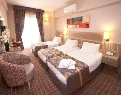 a hotel room with two beds and a chair at Nanda Hotel in Istanbul