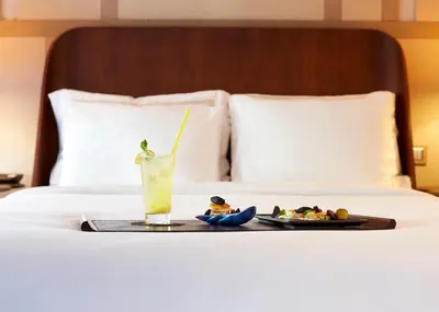a tray with a drink and a plate of food on a bed at The Stay Nisantasi in Istanbul