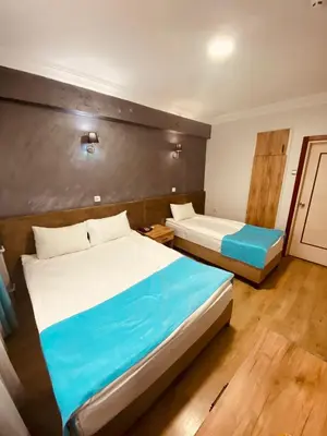 a bedroom with two beds and a wooden floor at Malkoç Hotel in Istanbul