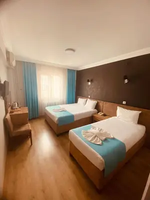 a hotel room with two beds and a chair at Malkoç Hotel in Istanbul