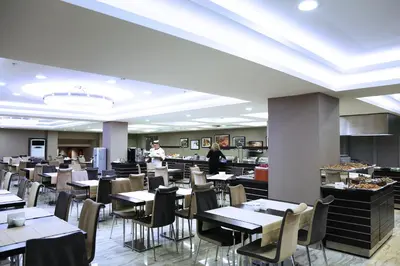 a restaurant with tables and chairs and a chef in the background at Benler Otel Laleli ISTanbul in Istanbul