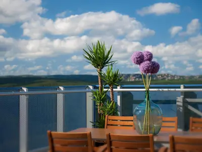 a table with purple flowers in a vase on a balcony at Somerset Maslak Istanbul in Istanbul