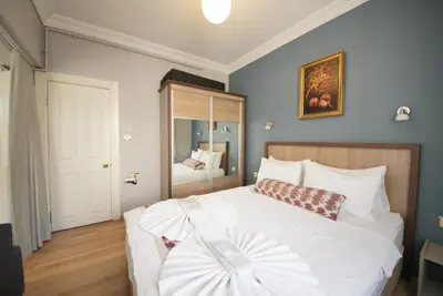 a bedroom with a large white bed and a mirror at Topkapi Apartments in Istanbul