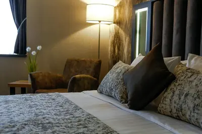 a hotel room with a bed with pillows and a chair at Hotel Anatolia in Bursa