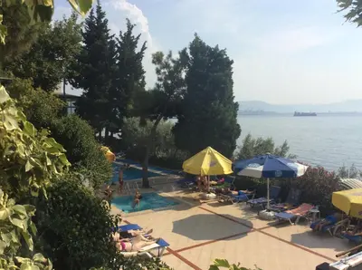a swimming pool with people sitting under umbrellas and the water at Atamer Doga Resort in Gemlik
