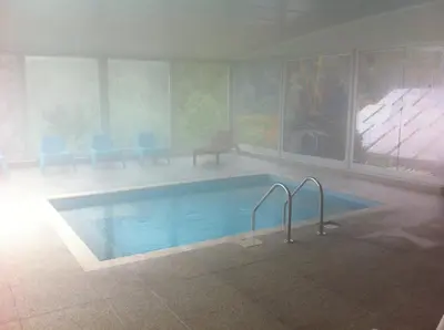 a swimming pool in a room with blue chairs at Atamer Doga Resort in Gemlik