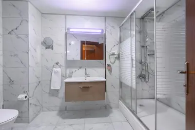 a white bathroom with a sink and a shower at Balturk Hotel Sakarya in Sakarya
