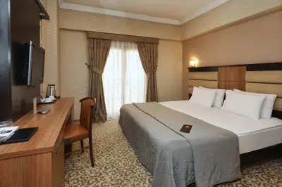 a hotel room with a bed and a desk and a television at New Balturk Hotel Izmit in Kocaeli