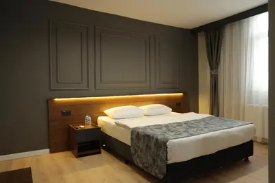 a bedroom with a bed with a headboard and a table at Turkuaz Hotel in Gebze