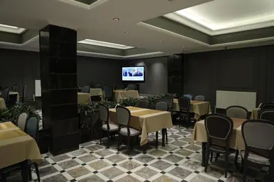 a dining room with tables and chairs and a flat screen tv at Turkuaz Hotel in Gebze
