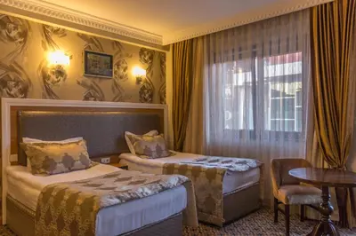 a hotel room with two beds and a table and a window at Grand Rosa Hotel in Istanbul