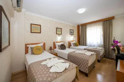 a hotel room with three beds with towels on them at Grand Ons Hotel in Istanbul