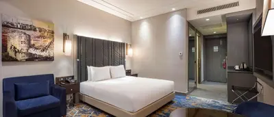 a bedroom with a white bed and a blue chair at Hilton Istanbul Bakirkoy in Istanbul