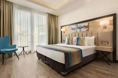 a hotel room with a large bed and a blue chair at Ramada Encore By Wyndham Istanbul Basin Express in Istanbul