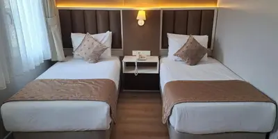 a hotel room with two beds and a table at Hotel Süreyya in Istanbul