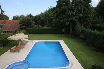 a swimming pool in a yard with chairs and an umbrella at Damla Pansiyon in Sapanca