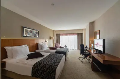 a hotel room with two beds and a desk at Crowne Plaza Istanbul Harbiye by IHG in Istanbul