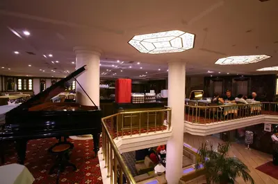 a lobby with a piano and a bar with people at Istanbul Royal Hotel in Istanbul