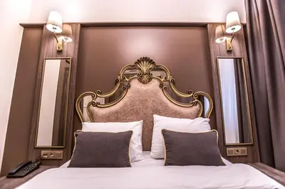 a bedroom with a large white bed with a gold headboard at Dara Old City Hotel in Istanbul
