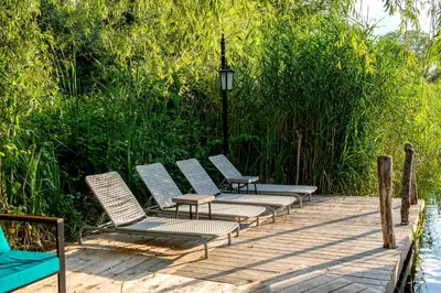 four chairs sitting on a wooden deck next to the water at Wineport Lodge Agva Riverside Hotel & Winery in Agva