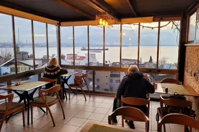 two people sitting at tables in a restaurant looking out at the water at Marmara Guesthouse in Istanbul