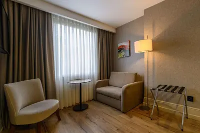 a hotel room with a chair and a table and a window at Ramada by Wyndham Istanbul Grand Bazaar in Istanbul