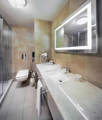 a bathroom with a sink and a toilet and a mirror at Titanic Comfort Sisli in Istanbul