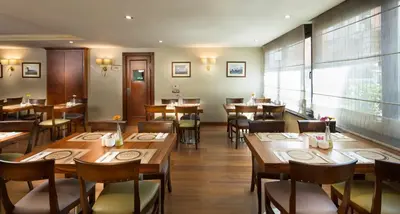 a restaurant with wooden tables and chairs and a large window at Titanic Comfort Sisli in Istanbul