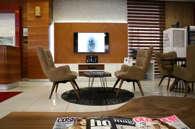 a lobby with chairs and a tv and a table at Hotel Avcilar City in Avcılar