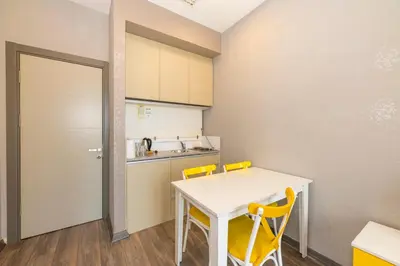 a kitchen with a white table and yellow chairs at Agora Suites in Esenyurt