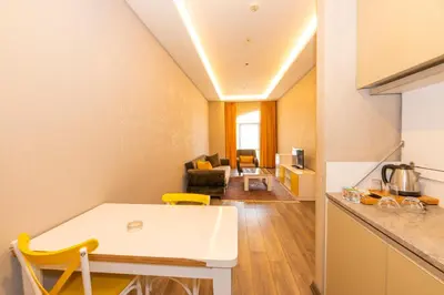 a kitchen and living room with a white table and yellow chairs at Agora Suites in Esenyurt