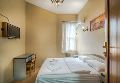 a bedroom with a bed and a desk and a television at Yeni Hotel in Istanbul