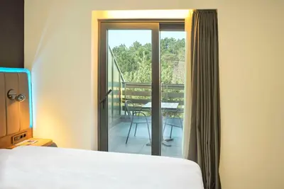 a bedroom with a bed and a balcony with a table at Park Inn by Radisson Istanbul Airport Odayeri in Istanbul