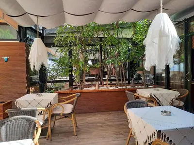 a restaurant with white tables and chairs and plants at Boyuguzel Termal Hotel in Bursa