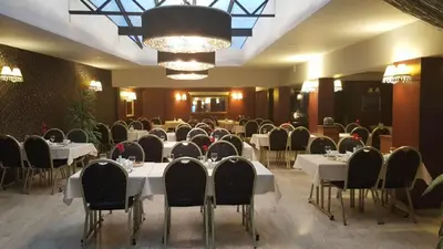 a dining room with white tables and chairs and a chandelier at Boyuguzel Termal Hotel in Bursa
